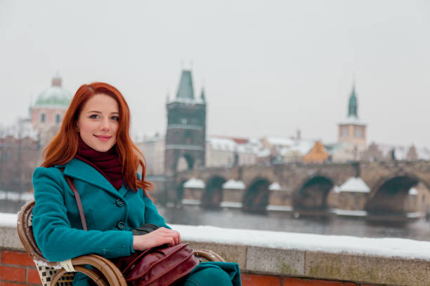 junge rothaarige mädchen sitzen auf stuhl mit old town prague city - people winter urban scene chair stock-fotos und bilder