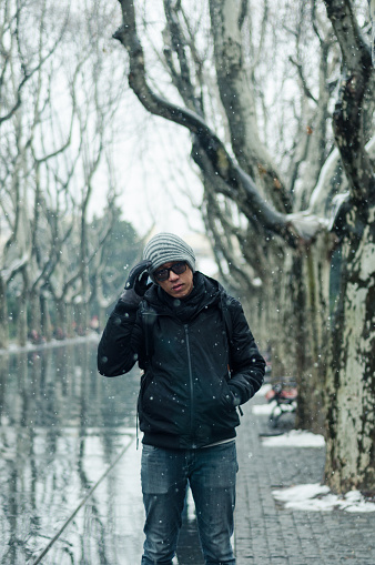 male tourist standing in Xiangyang park on middle Huaihai road, Shanghai in winter during snow