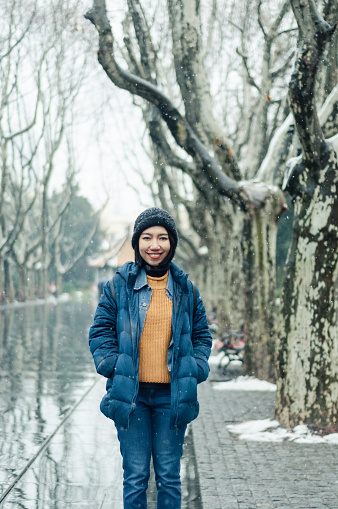 female tourist standing in Xiangyang park on middle Huaihai road, Shanghai in winter during snow