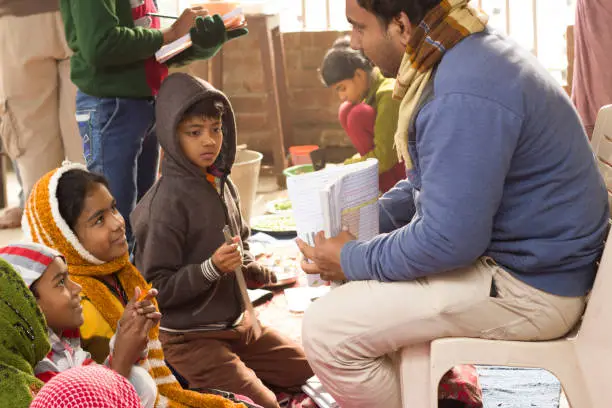 Photo of Teacher explains to students, holding exercise book.