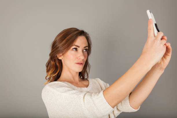 istock pretty women taking a selfie with a smartphone on gray background 927672566
