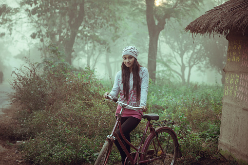 Beautiful young women standing with bicycle near misty Forest in winter wear.