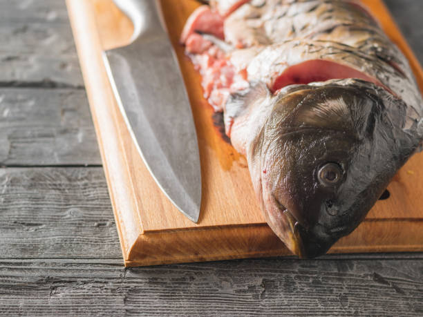 istock Cut into pieces carp fish with a knife on a cutting Board. 927682200