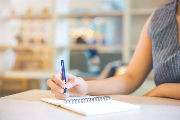istock Business woman hand is writing on a note pad with a pen. 927700014
