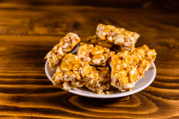 istock Ceramic plate with peanut brittles on wooden table. 927702570
