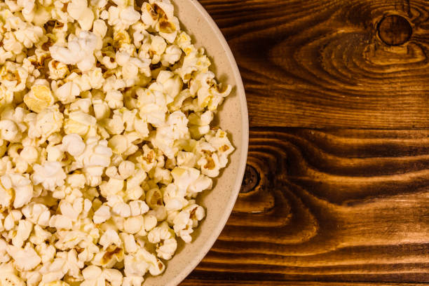 istock Ceramic plate with popcorn on wooden table. Top view 927702580