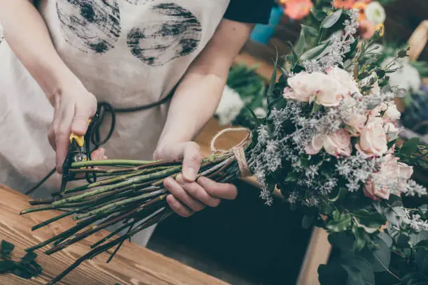 Photo of Crop florist arranging bouquet on counter