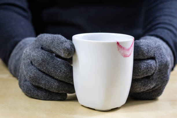Empty white mug with gloves. Hands in warm gloves holding a china mug on a wooden kitchen table. Light background.