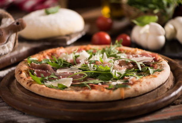 istock Italian Pizza with rocket salad on wooden table 927753410