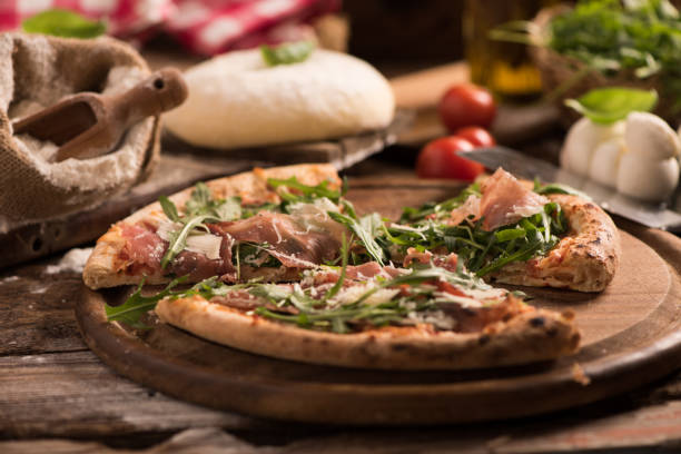 istock Italian Pizza with rocket salad on wooden table 927756494