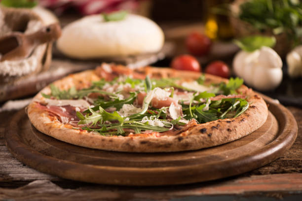istock Italian Pizza with rocket salad on wooden table 927756660