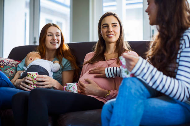 istock Friends with baby boy sitting on sofa at home 927760036