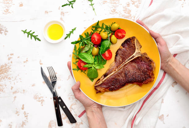 istock T-bone steak ready to eat, served on a plate, view from above 927760432
