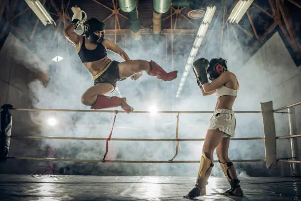 Determined female boxers having a fight during a kickboxing match in a ring.