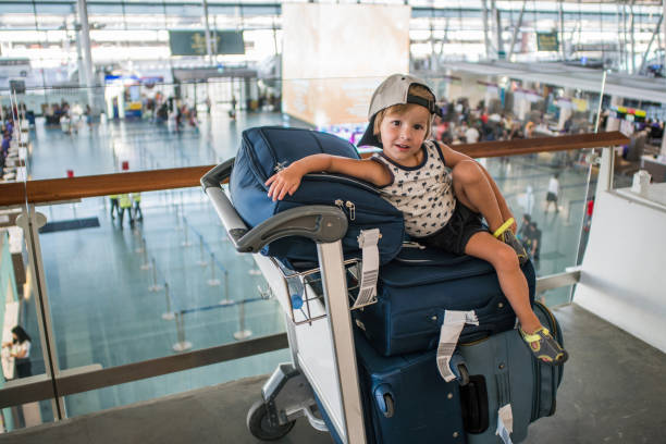 istock Small boy sitting on suitcases while waiting for his flight at the airport. 927772356