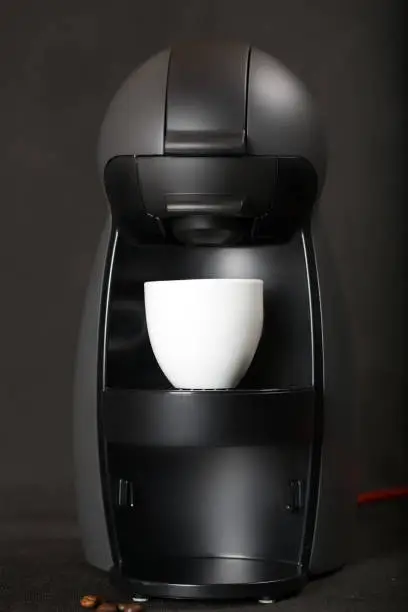 Black coffeemaker and coffee capsules on a black background. Closeup