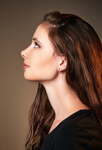 A profile portrait of a classically beautiful young brunette woman with a long, swanlike neck.