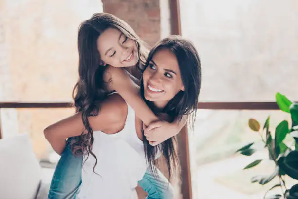 We are fooling around, the most cool time together! Happy delightful mother is holding daughter on her back