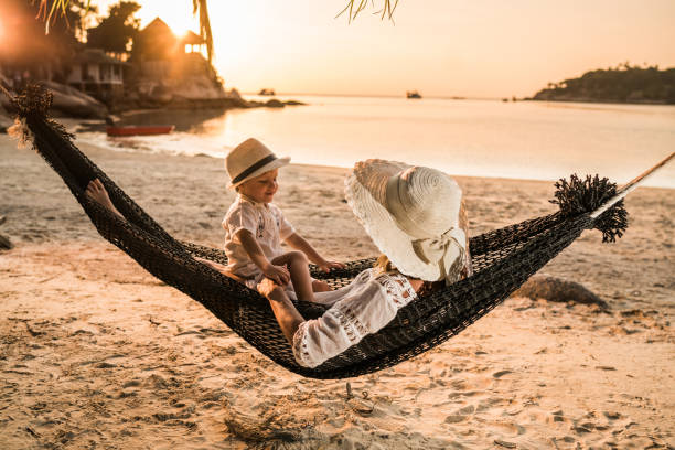 small boy talking to his mother in a beach hammock at sunset. - hammock beach vacations tropical climate imagens e fotografias de stock