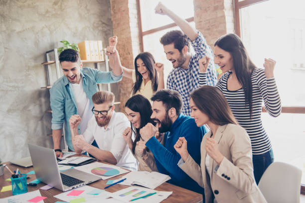 erfolg und team arbeiten konzept. gruppe von geschäftspartnern mit erhoben händen in hellen modernen arbeitsplatz, feiert den durchbruch in ihrem unternehmen - celebration success business computer stock-fotos und bilder