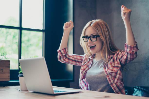 istock Work complete. Young, blonde, specialist rejoicing her finished work with raised fists sitting at her desk 927809432