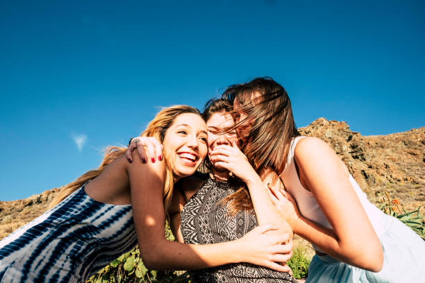 istock three young women hug themselves in a sunny day. 927813658