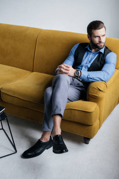 istock stylish man sitting on yellow sofa 927817234