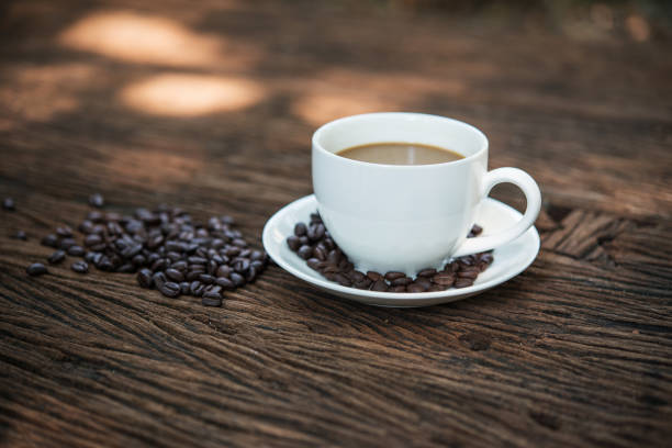 Coffee cup and coffee beans on wooden table.