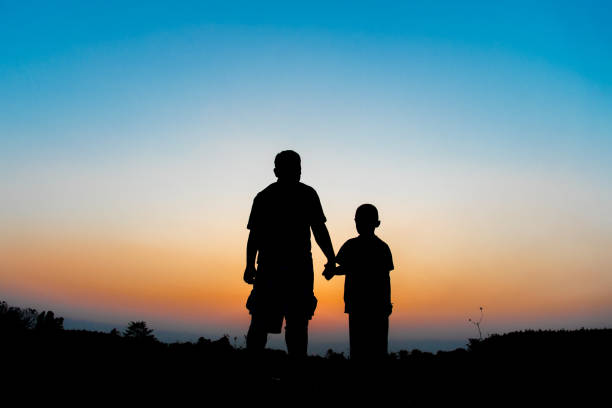 istock Silhouette Father and son hold hands in evening time 927820994