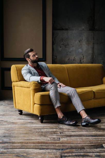 istock handsome stylish elegant man sitting on couch in loft interior 927821048