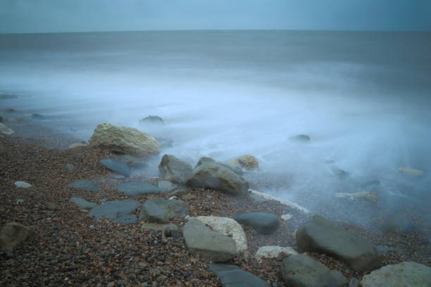 Stones on the pebble beach with blurred sea waves near town of Seaton in East Devon on the Jurassic Coast natural World Heritage Site during storm Emma on early March 2018