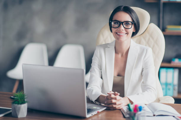 retrato de confianza empresaria hermosa exitosa inteligente con chaqueta blanca, ella está sentada en frente del ordenador en su puesto de trabajo - economist fotografías e imágenes de stock