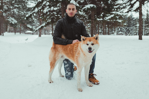 Handsome man with Akita dog on a beautiful winter day in nature