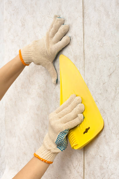 istock hands with spatula smoothing wallpaper on the wall 927840016