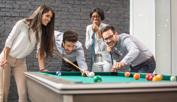 istock Cheerful business people playing billiards during office break. 927840100