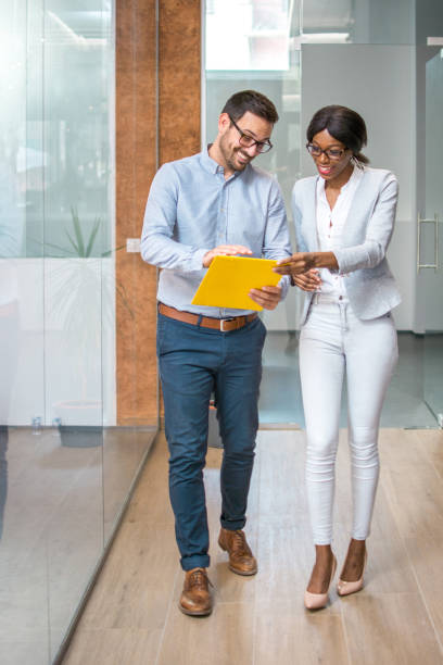 istock Happy business people walking through office hallway and discussing papers. 927840194