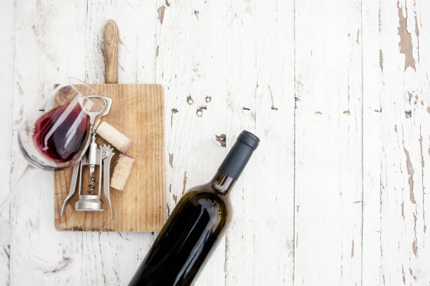 a glass of red wine, bottle, corkscrew  and wine corks on rustic board over  white wooden table, copyspsce. wine tasting concept"n - cork tops imagens e fotografias de stock