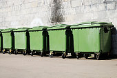A row of green garbage containers on the city street.