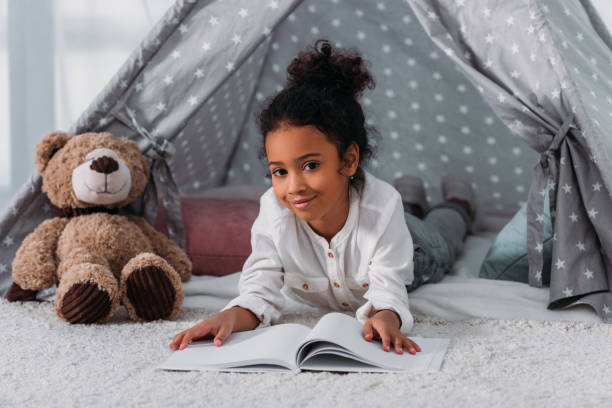istock african american kid lying with book and looking at camera 927848680