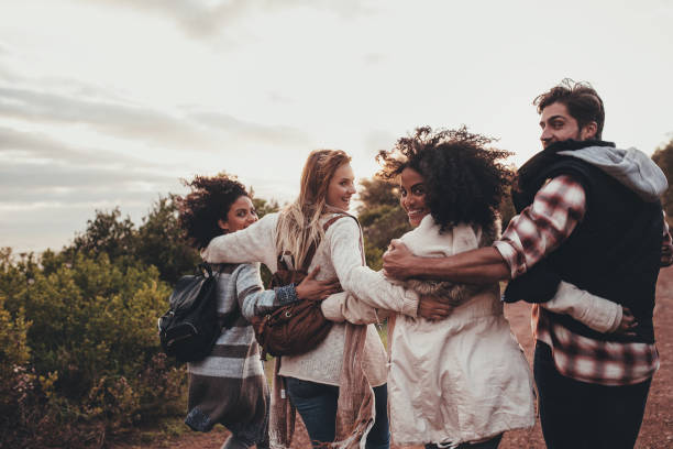Group of friends hiking on a holiday Friends hiking in nature. Group of man and women walking together in countryside. Happy young people turning around and looking at camera. falling behind stock pictures, royalty-free photos & images