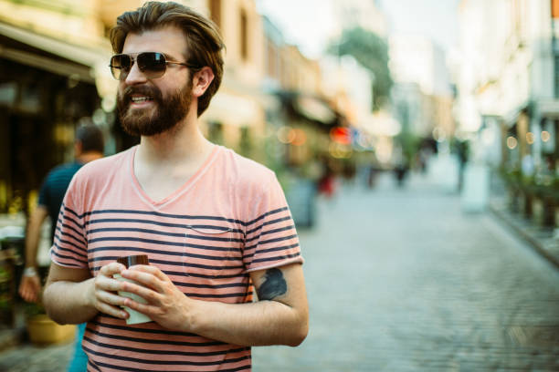istock Handsome man walking through the city streets and drinking coffee 927856920