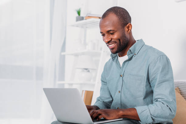 istock happy african american man using laptop on sofa at home 927859942