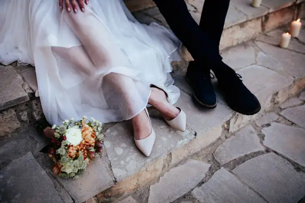 Photo of Romantic newlywed bride and groom sitting on stone steps