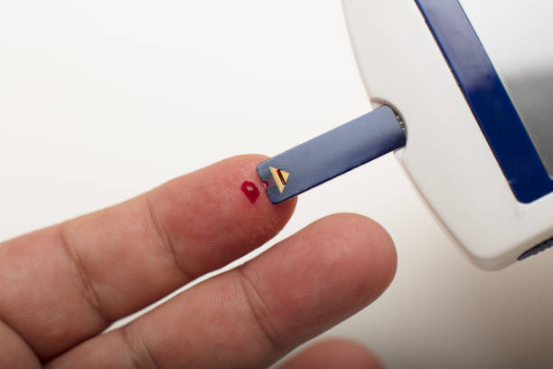 Diabetic taking a blood sample from his finger stock photo