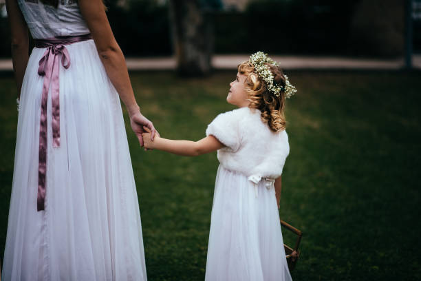 Little flower girl with flower basket holding hands with bride Close-up or little bridesmaid with flowers basket holding hands with bride and looking at her flower girl stock pictures, royalty-free photos & images