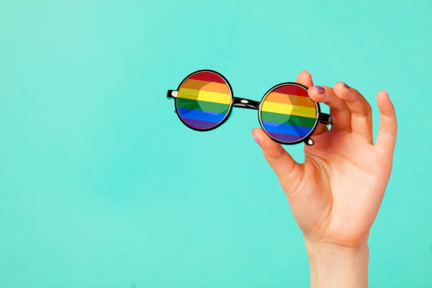 istock Female hand holding glasses with rainbow flag 927863396