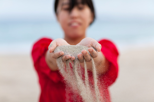 A young woman is dropping sands from her hands.