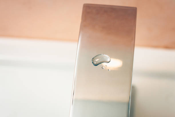 istock Glossy smooth chrome-plated surface mixer with a drop of water in the bathroom 927876766