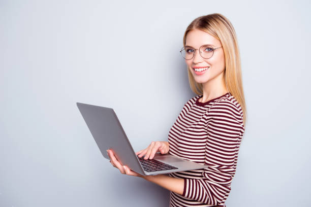 istock Cute charming confident and smiling young lady is holding laptop and having a video conversation via webcam, isolated on grey background 927883316