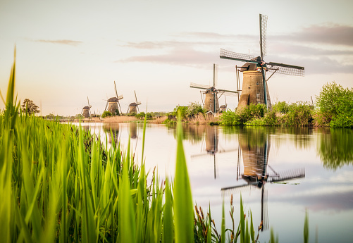 A long exposure image of old-fashioned Dutch windmills by a canal, near the village of Kinderdijk in Holland.